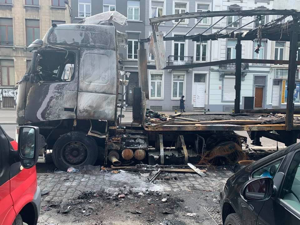 Brussels officials struggle to tow a burned-out truck