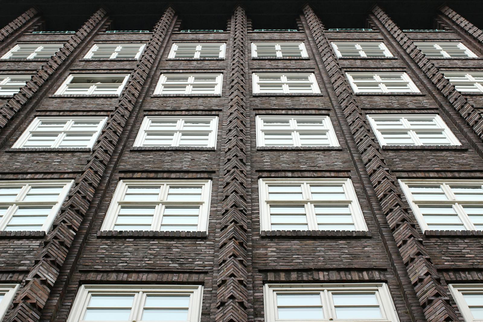 A striking low angle shot of a brick building showcasing architectural details and symmetry.