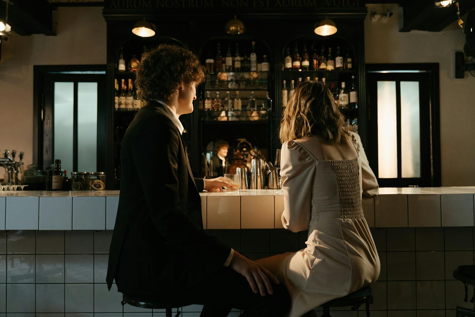 A couple seated at a bar, engaged in conversation in an elegant setting.