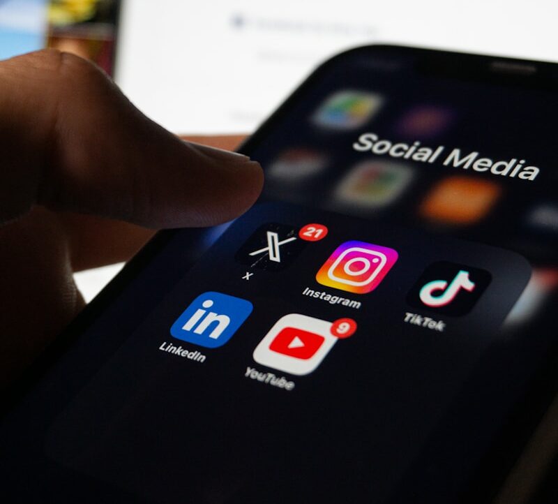 A person holding a smart phone with social media on the screen